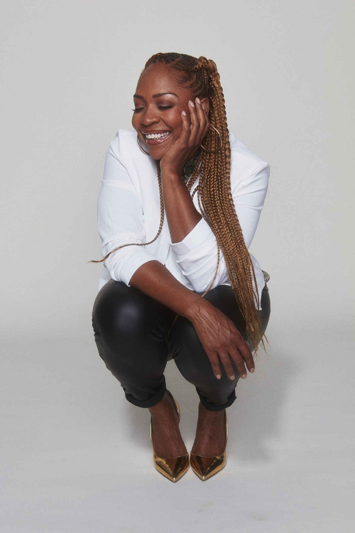 Divine Brown in a denim jacket, laughing with her hand in her hair