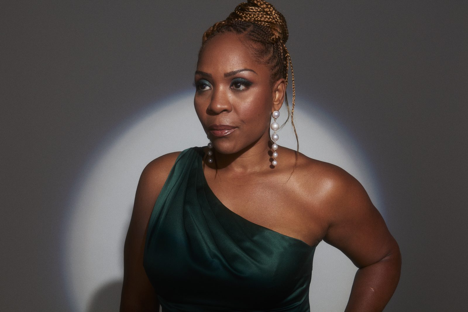 Divine Brown seated in a gold and black floral gown, laughing